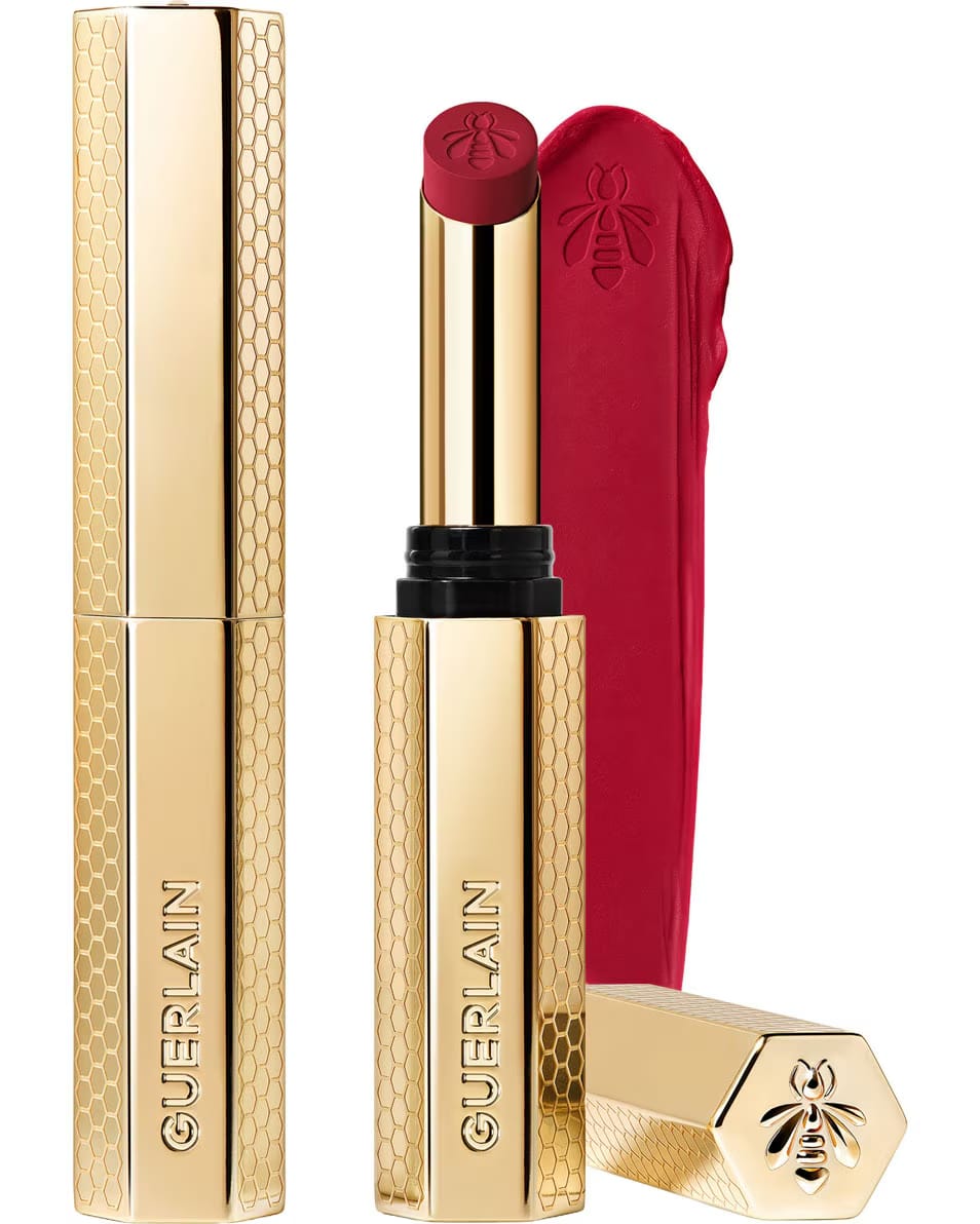 Guerlain KissKiss Honey-Infused Matte Lipstick in its signature slim golden honeycomb case, alongside an open ruby-red lipstick bullet and creamy velvety texture smudge, available at blue salon.