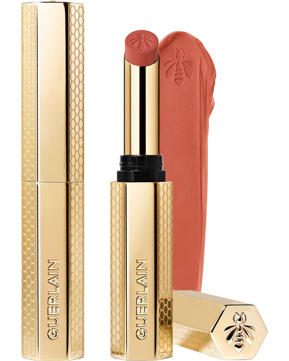 Guerlain KissKiss Honey-Infused Matte Lipstick in its signature slim golden honeycomb tube, featuring an open nude-pink lipstick bullet next to a creamy texture smudge, available at blue salon.