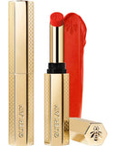 Guerlain KissKiss Honey-Infused Matte Lipstick in its signature slim golden honeycomb case, alongside an open vibrant coral-red lipstick bullet and creamy velvety texture smudge, available at blue salon.