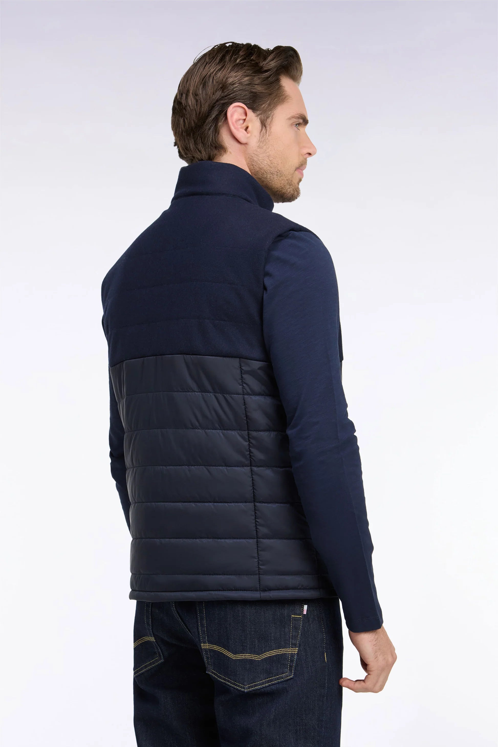 Dark blue sleeveless vest with a high collar. The upper back is solid fabric, and the lower back is horizontally quilted.