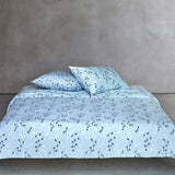 Light blue duvet cover and two pillow cases with a pattern of small white and dark blue plant stems.