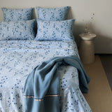 Light blue duvet cover and four pillow cases with a scattered pattern of small dark blue and white floral elements.