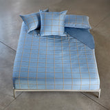 Light blue duvet cover and two pillow cases with a white and dark grid pattern.