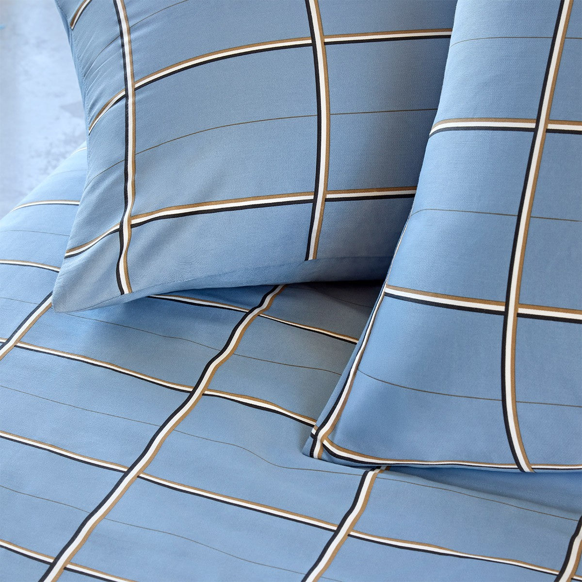 Light blue duvet cover and pillow case with a grid pattern of white, black, and brown lines.