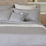 Grey/white striped duvet cover and two pillows with brown DoubleB logo. Solid grey pillow with white 'B' logo. White striped