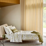 Jadeite green duvet cover and two pillows with white floral patterns. One olive green striped pillow, one plain beige pillow,