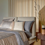 Taman duvet cover and pillowcases with brown, beige, and gray vertical stripes. Gray flat sheet and pillow, plus a beige logo