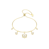 A high-resolution direct frontal studio shot of the Swarovski Magic bracelet laid out on a white surface, displaying its radiant central snowflake charm, flanking star motifs, and adjustable gold-finished sliding chain.