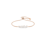 A high-resolution studio shot of the Swarovski Mesmera bracelet laid out on a white surface, displaying its central cluster of mixed-cut white crystals and its adjustable rose gold-finished chain.
