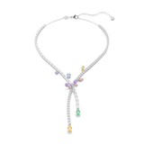 A high-resolution front studio view of the Ariana Grande x Swarovski necklace, showing the elegant crossover design, the pastel-colored crystal dragonfly, and the cascading clear strands finished with yellow and green pear-cut droplets.