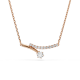 A high-resolution front studio view of the Swarovski Matrix necklace centerpiece, highlighting the asymmetric crossover design of the white crystal curve and the polished 18K rose gold-plated drop-stone bar.
