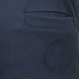 Dark blue fabric trousers with a horizontal pocket opening and a circular embossed logo of a soccer player with a ball.