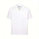 White short-sleeved shirt with a Cuban collar, button-down front, and a chest patch pocket with subtle tone-on-tone embroider
