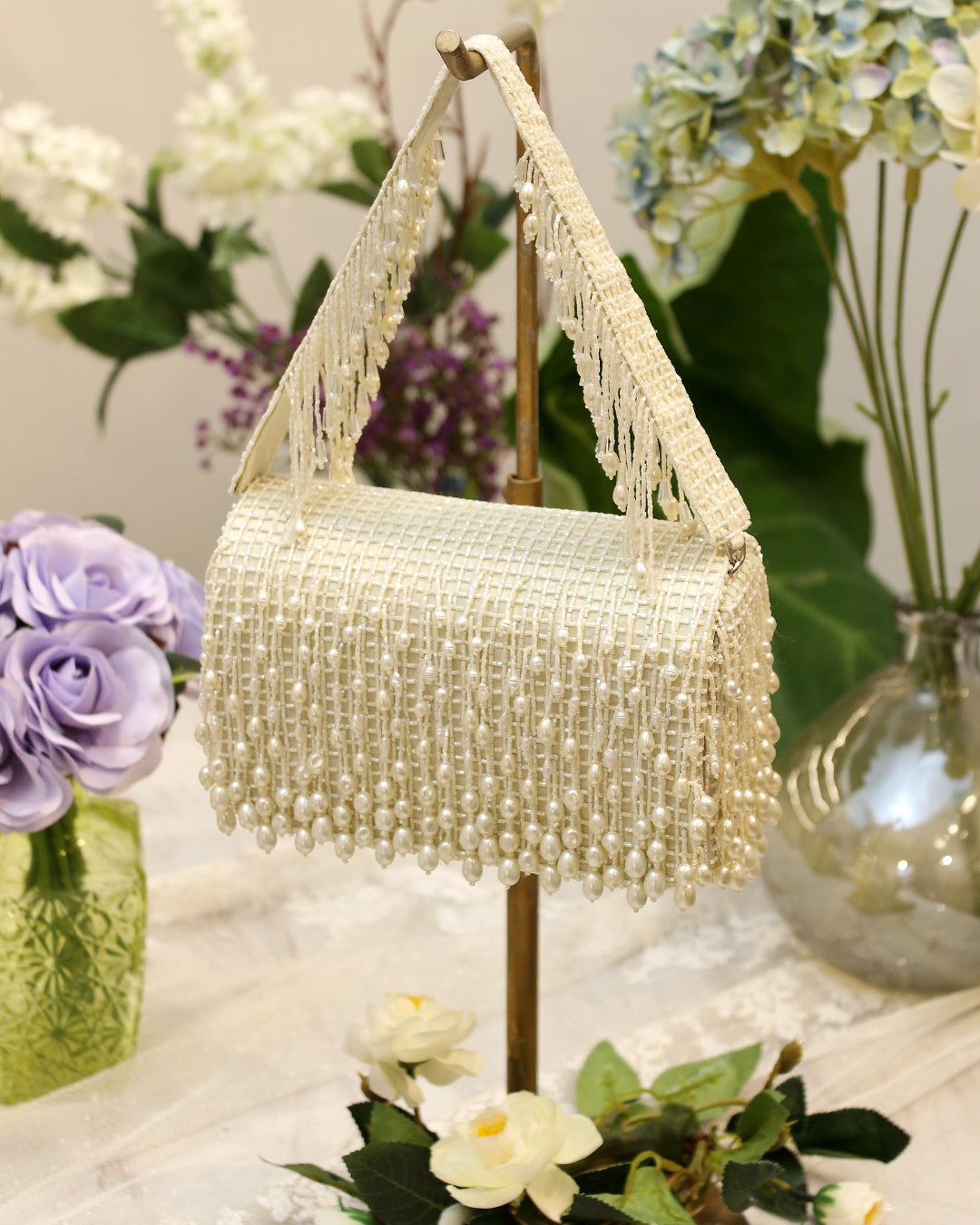 Pristine ivory flapover clutch with a woven body and handle, both adorned with dense fringes of pearlescent beads.