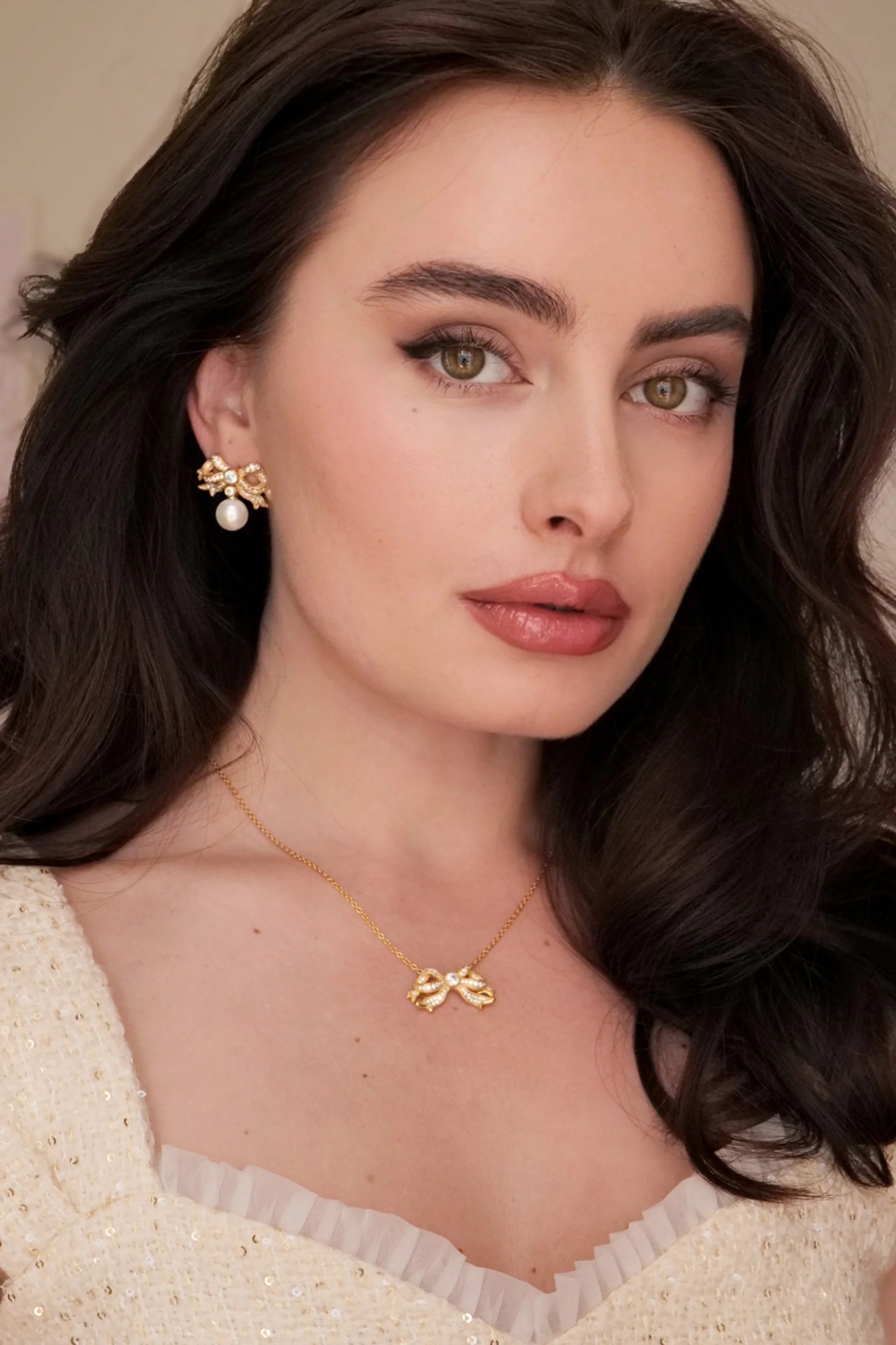 Gold-toned necklace with a bow-shaped pendant, adorned with clear rhinestones and a larger clear stone at its center.