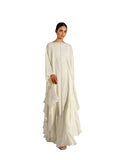 A woman modeling a Velvety brand off-white two-piece set. The inner gown is covered in silver sequin wave patterns, while the outer chiffon layer features dramatic cascading ruffles and a fluid, tiered hemline.