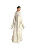Back view woman modeling a Velvety brand off-white two-piece set. The inner gown is covered in silver sequin wave patterns, while the outer chiffon layer features dramatic cascading ruffles and a fluid, tiered hemline.