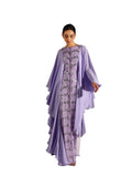A woman modeling a Velvety brand lavender two-piece set. The inner gown is covered in silver sequin wave patterns, while the outer chiffon layer features dramatic cascading ruffles and a fluid, tiered hemline.