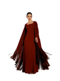 A woman modeling a Velvety brand burgundy two-piece set consisting of a sleek square-neck column dress and a matching long-sleeved sheer outer cape with heavy fringe detailing at the hem.