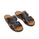 Pair of black leather slip-on sandals with tan footbeds and black soles. Each has two wide straps, one with a silver-toned bu