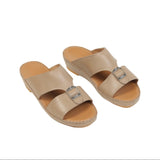 Pair of beige leather slide sandals with two wide straps and silver-toned buckles. Light brown footbed with visible stitching