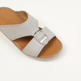 Light grey leather slip-on sandal with a wide upper strap, silver-toned buckle, tan insole with white stitching, and embossed