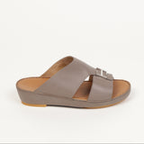 Taupe leather slip-on sandal with two straps, a contoured tan footbed, and a silver-toned rectangular buckle.
