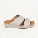 Light grey leather slip-on sandal with two crossing straps, silver-toned buckle ornament, light brown footbed, and grey wedge