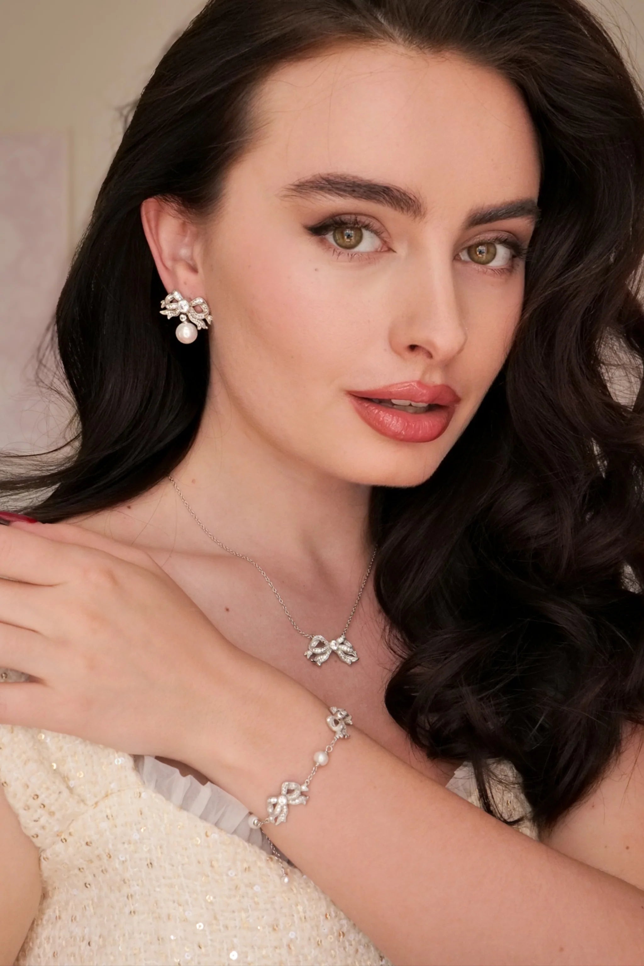 Silver-toned necklace with a bow pendant encrusted with clear stones and a small pearl in the center.