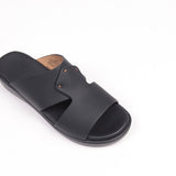 Black matte slide sandal with two overlapping straps, secured by two small brown studs. Flat black sole.