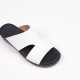 White slide sandal with a wide upper, two straps, one overlapping. Black footbed and sole. Small oval detail on the top strap