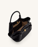 Black pebbled faux leather mini tote bag with two top handles, white contrast stitching, gold-toned rectangular clasp, and li