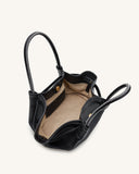 Black pebbled tote with white contrast stitching on handles and edges. Open top, light tan interior, black slip pocket with g