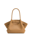 Tan pebbled leather tote bag with a single top handle, winged sides, and a front strap with a gold-toned rectangular buckle.