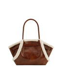 Brown leather-look tote bag with two top handles and cream shearling-style trim along the top edge and folded sides.