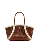 Brown leather tote bag with white fluffy trim along the top and sides, two top handles, and a gold-toned clasp on the front.