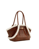 Brown leather tote bag with white faux shearling trim, two top handles, and a gold-toned rectangular clasp.