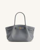 Grey pebbled leather tote bag with two top handles, a gold-toned rectangular clasp, and white contrast stitching on front str