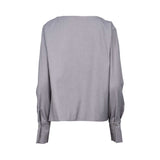 Grey long-sleeve top with asymmetrical neckline, draped fabric detail, and metallic button accent on the shoulder, displayed on a white background.