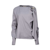 Grey long-sleeve top with asymmetrical neckline, draped fabric detail, and metallic button accent on the shoulder, displayed on a white background.