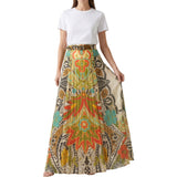 A woman modeling a long, pleated maxi skirt with a vibrant bohemian paisley pattern in green, orange, yellow, and blue, paired with a white t-shirt against a plain white background.
