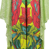 Lime green dress with a vibrant, glittery floral and foliage print. Sheer, sequined lime green panels drape on the sides.