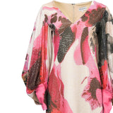 Sequined V-neck dress with abstract pink, white, brown, and black print. Wide sleeves gather at bright pink cuffs.