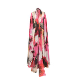 Long flowing dress with a vibrant pink, red, black, white, and beige floral print. Halter V-neck, tie-waist, and cape-like sl