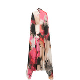 Flowing chiffon dress with a high neck, abstract pink, black, and white floral print, and long cape-like panels. Cream waist