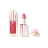 Clear rectangular lip gloss bottle with rose-toned liquid and bubbles. It has a faceted rose-toned cap and a white applicator