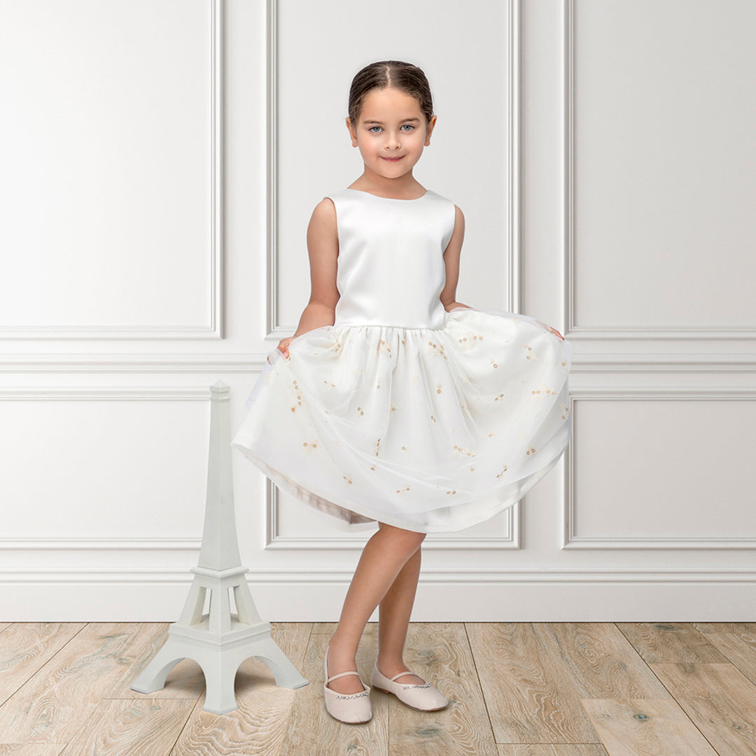 A luxury ivory occasion dress shown alongside a Jules & Juliette Paris 3-piece baby gift set in grey Toile de Jouy.