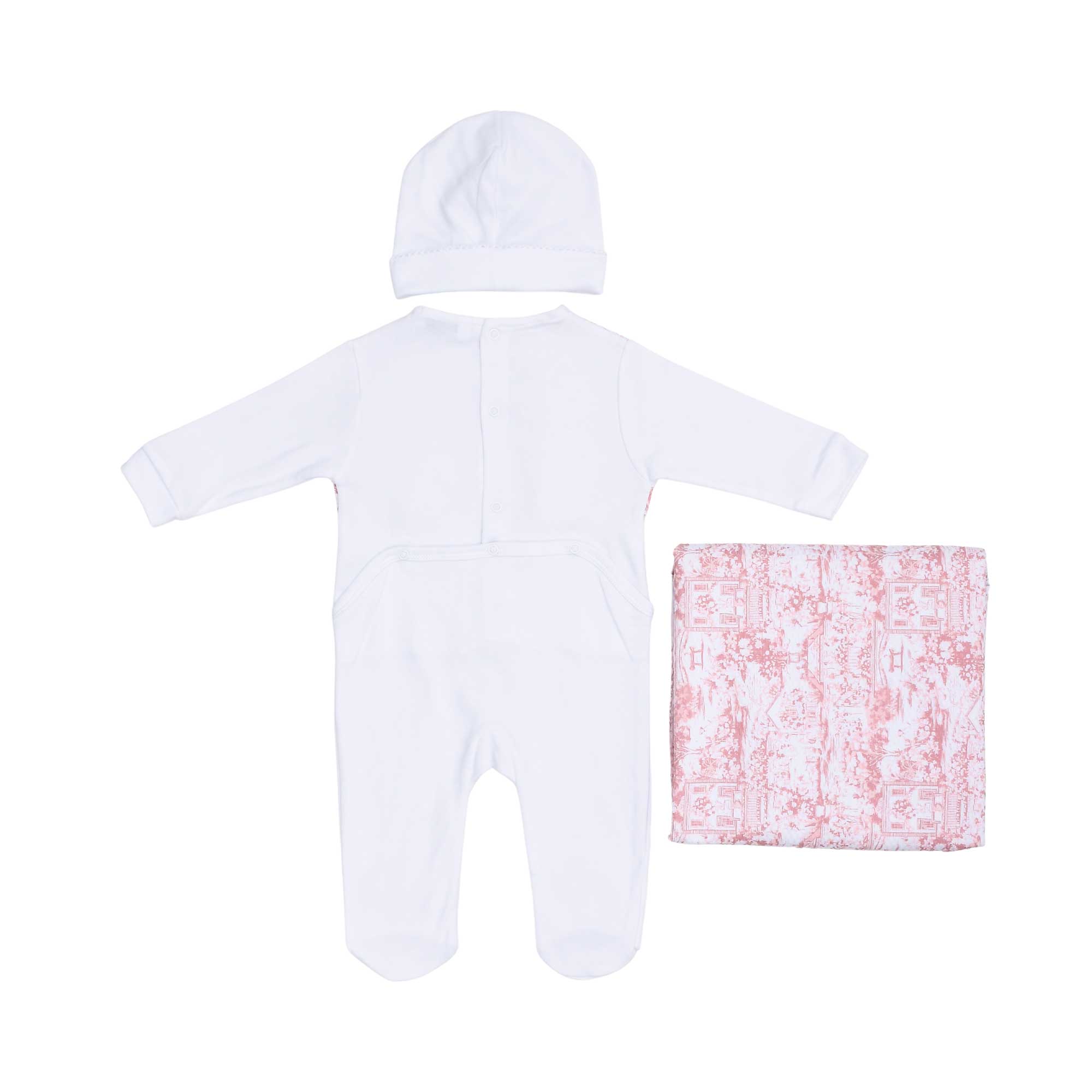 Back view of the baby sleepsuit showing the snap fasteners, accompanied by the white beanie and folded pastoral print blanket.