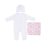 Back view of the baby sleepsuit showing the snap fasteners, accompanied by the white beanie and folded pastoral print blanket.