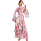 Full-length studio shot of a model wearing the Julytow abstract print maxi dress with long bell sleeves and a tiered skirt, tied at the waist with a sash.